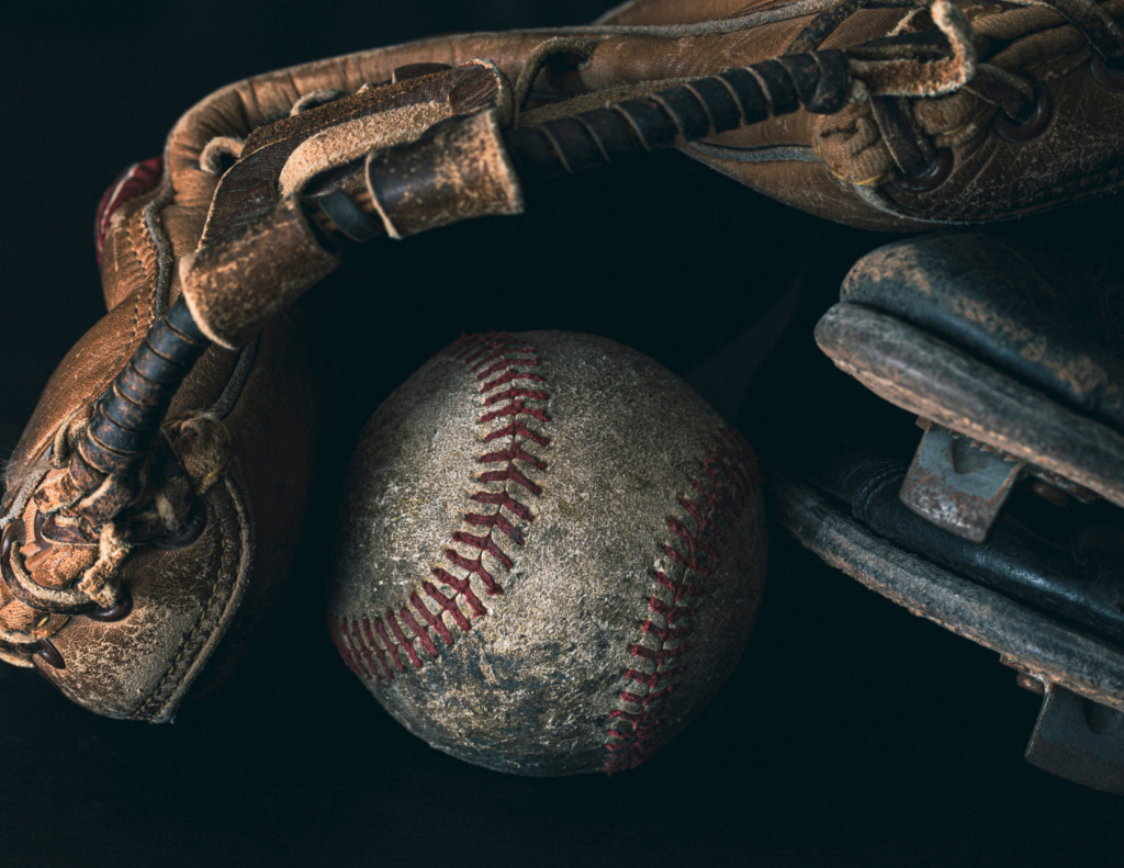 An old baseball glove covering a dirty baseball.