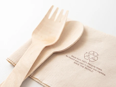 A bamboo fork and spoon on a recycled brown napkin.