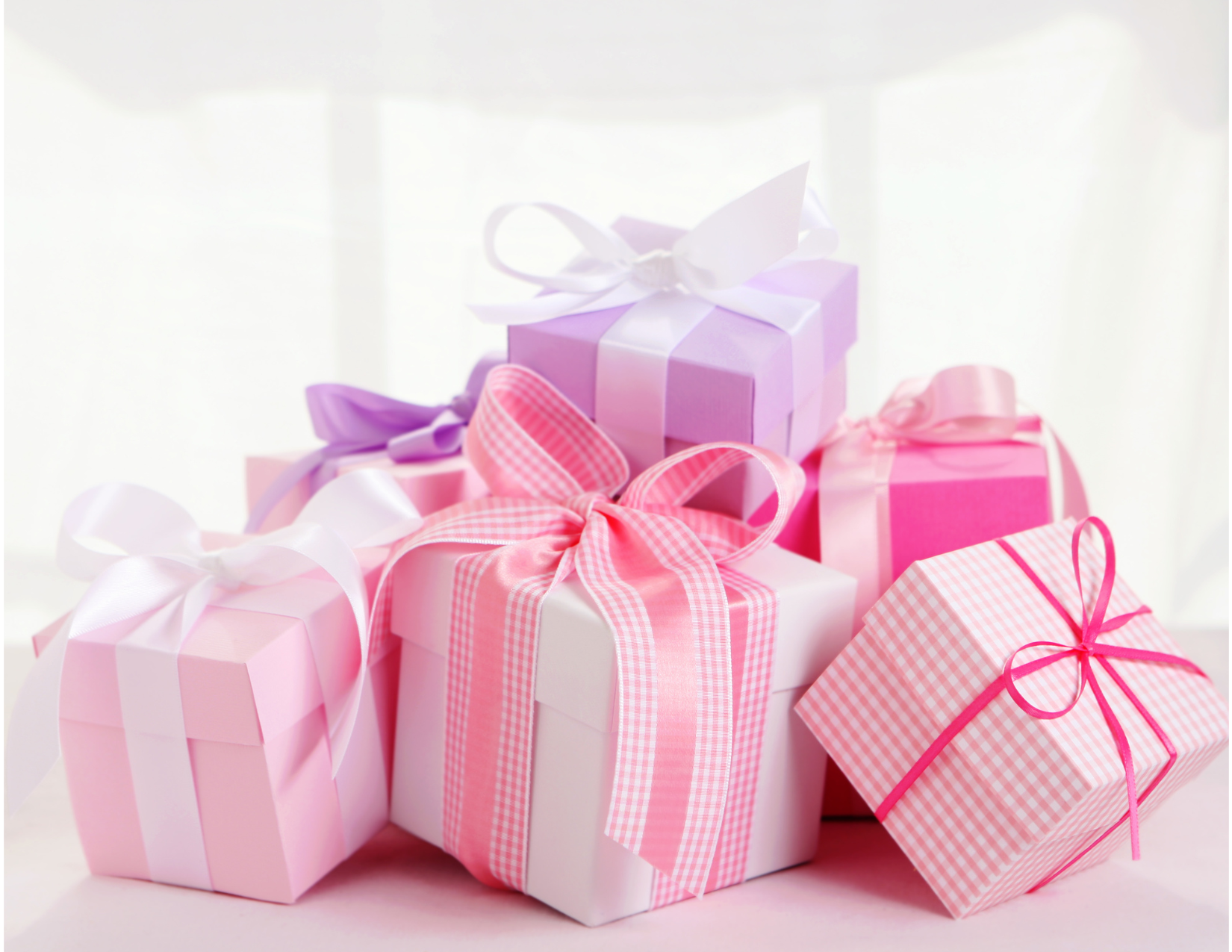 Pink checkered gift boxes with giant pink bows plus a purple box with a white bow.