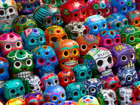 Rows of Day of the Dead ceramic skulls painted in multi colors with painted on teeth and flowers and other motifs.