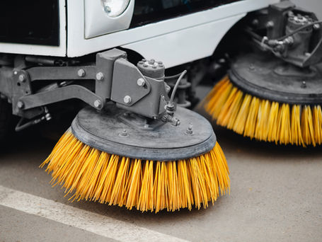 Yellow brush scrub machinery off the back of a street sweeping truck.