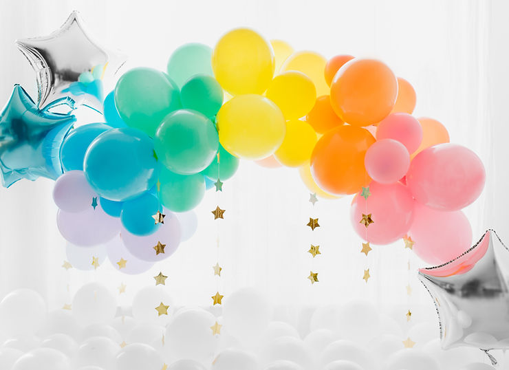 Rainbow balloon arch with gold shiny stars cascading down and silver and blue shiny star balloons to the sides.