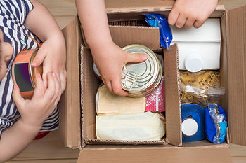 Food donation boxes with kids putting cans into the boxes.