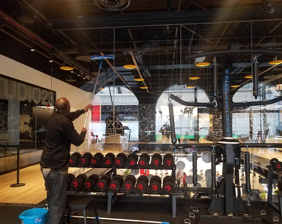 One of PopUP CleanUP's cleaners wiping down the mirrors in front of a rack of weights at a Nike branding event.