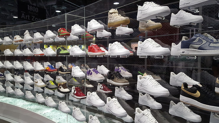 A curved display case filled with Nike shoes, mostly all white that are waiting to be customized at a Nike Event.