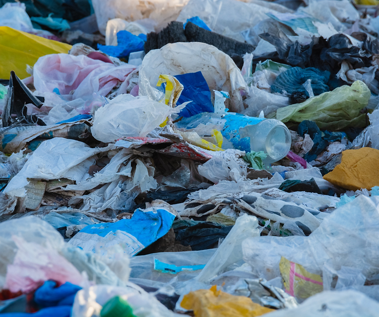 Piles of trash, including torn and ripped plastic bags spilling trash into the environment.