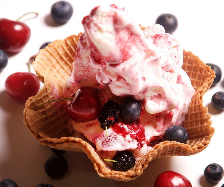 Cherry ice cream in a waffle bowl topped with cherries, blueberries and blackberries.