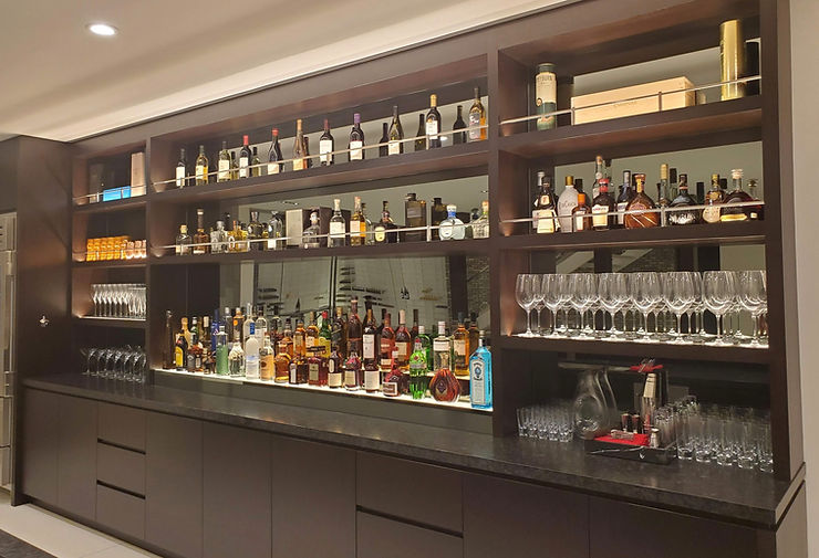 A bar at a private home stocked with many alcohol bottles and wine glasses.