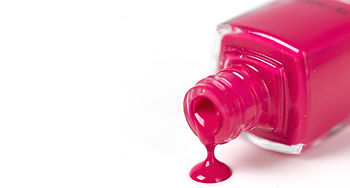 Dripping pink nail polish spilling onto a white surface.  