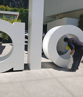 A PopUp CleanUp cleaner wiping the interior of the "o" on the alo yoga sign at a branding activation