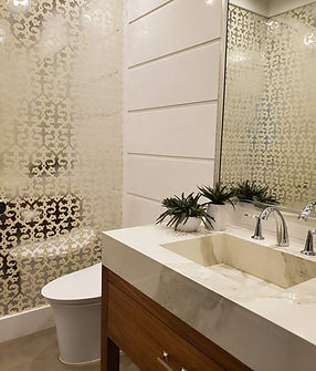 A clean fancy bathroom with a farmhouse marble sink, modern toilet, and gold pattern decorated shower glass wall.