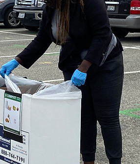 A PopUp CleanUp cleaner wearing all black and blue gloves emptying and relining a cardboard trash can.