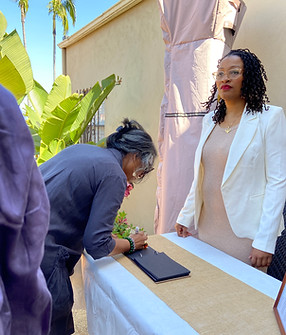 A woman standing at a desk behind a table for check in registry at a wedding