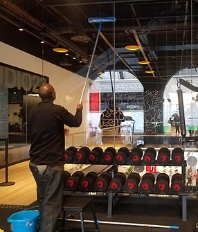 A popUP cleaner taking a squeegee to mirrors in front of a rack of weights at a gym at a Nike branding activation