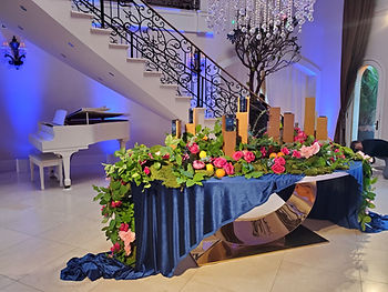 A table set up with flowers and Secret Deodorant products in front of a white grand piano and an ornate spiral staircase in a Beverly Hills Mansion for a branding activation for P&G.