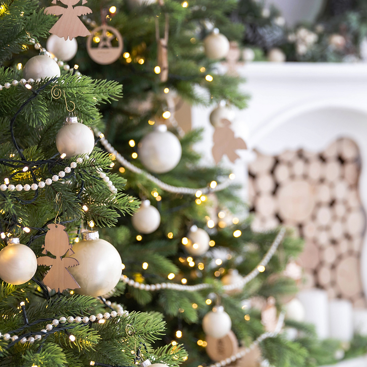 A Christmas tree with white balls, white pearl strands, angel ornaments, and yellow twinkling lights.