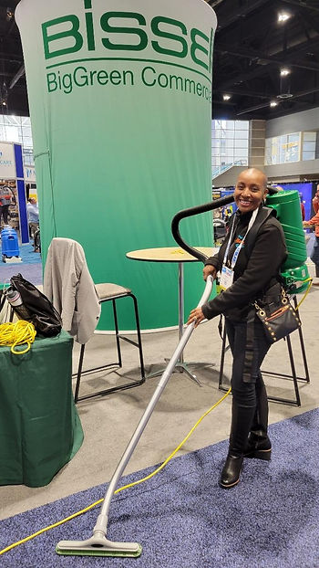 CEO Kenetia Lee modelling a green backpack vacuum at the 2022 ISSA show.