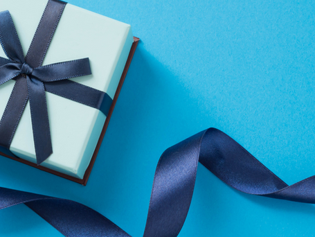 A white gift box wrapped in blue ribbon on a medium blue background.