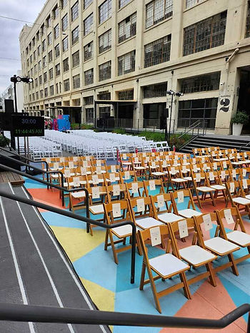 Rows of folding wood chairs on a blue, yellow, and orange mat lined up at The Row in DTLA for the Popsugar branding activation.