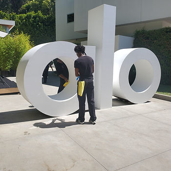 One of PopUP CleanUP's cleaners wiping down the alo yoga sign at a branding activation at a private home.