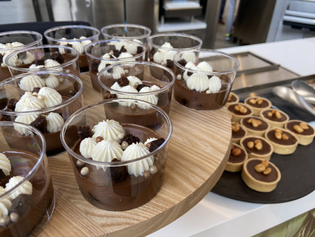 Two platters of chocolate desserts: chocolate mousse topped with whipped cream swirls and chocolate ganache wrapped in pastry at the FêteLA SoFi Stadium Event.