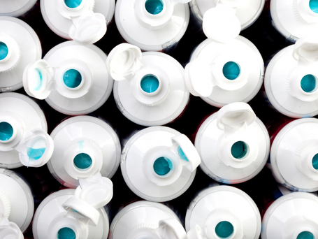 Caps of bleach cleaner bottles open to show the bright blue cleaning gel.