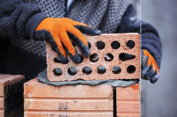 Bricklayer setting a brick with cement.