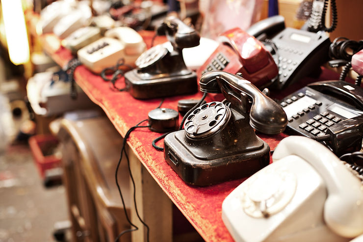 A table filled with old telephones from the dial up land line kinds to the multi channel office phones.  Old stuff to get rid of during Spring Cleaning and where it should go.