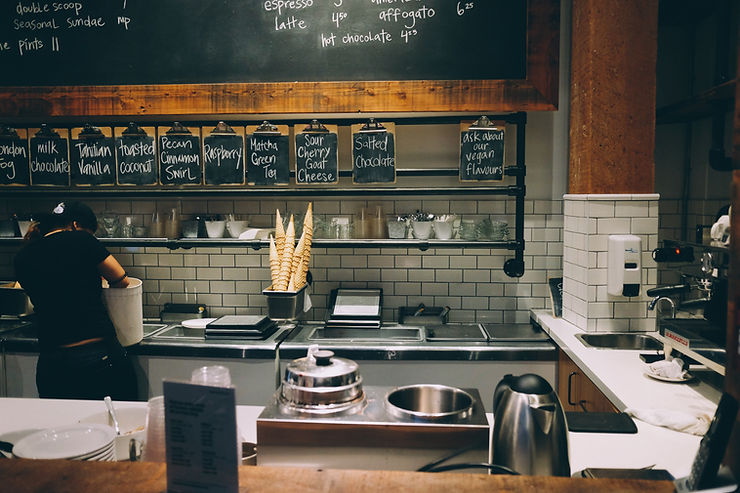 A very clean coffee shop kitchen with white tile, wood walls, and stainless steel counters. It's important to keep kitchens spotless like this to minimize cross-contamination.