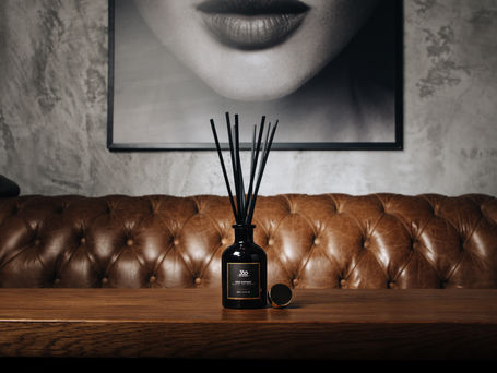 A brown leather sofa in front of a wood table with scented diffuser under a black and white photo showing only a woman's big lips.