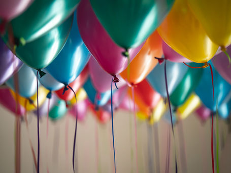 A multicolored sea of balloons: pink, orange, yellow, green, blue, floating on the ceiling with the strings trailing down.