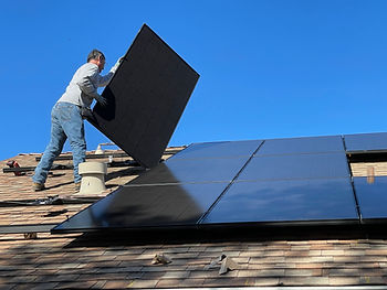 A man installing solar panels onto a tile roof.