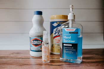 Clorox, Lysol wipes, and Hand sanitizer on a wooden counter.