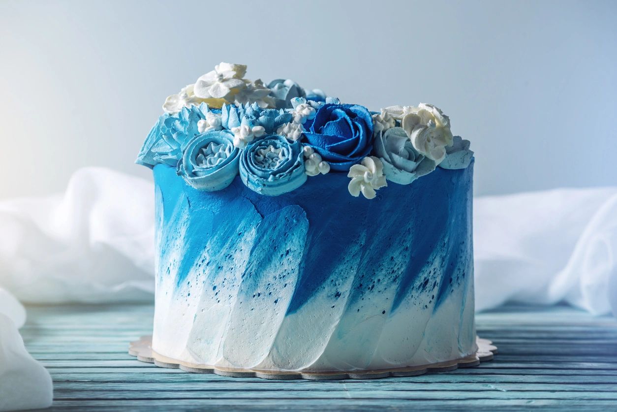 Elegant blue and white cake decorated with icing flowers.