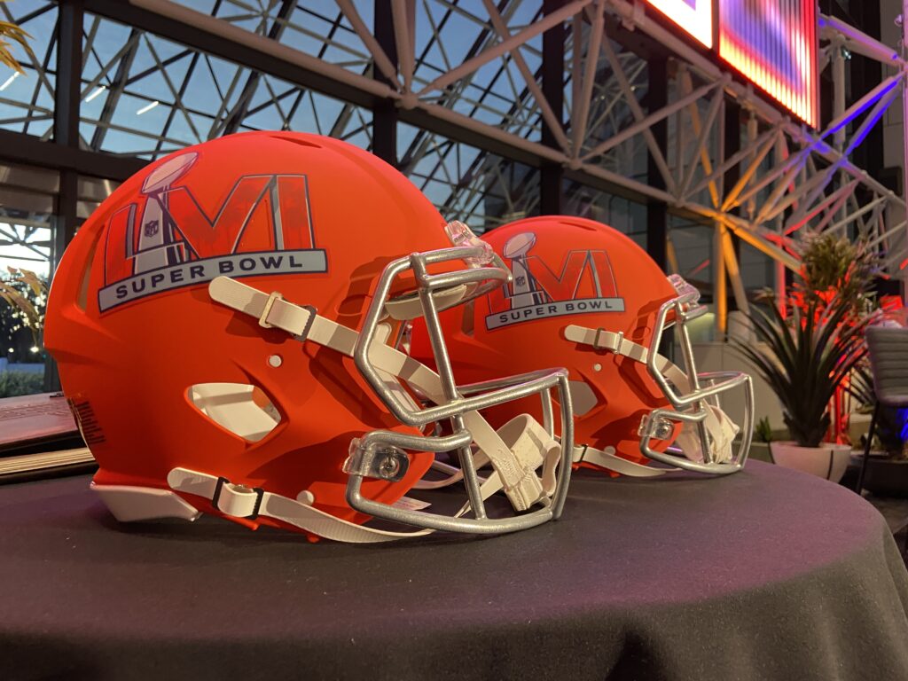 Two bright orange Super Bowl LVI helmets placed on a table at an NFL Business Connect event.