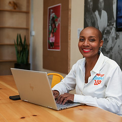 Kenetia Lee, CEO of PopUp CleanUp working on her laptop at a wood table.