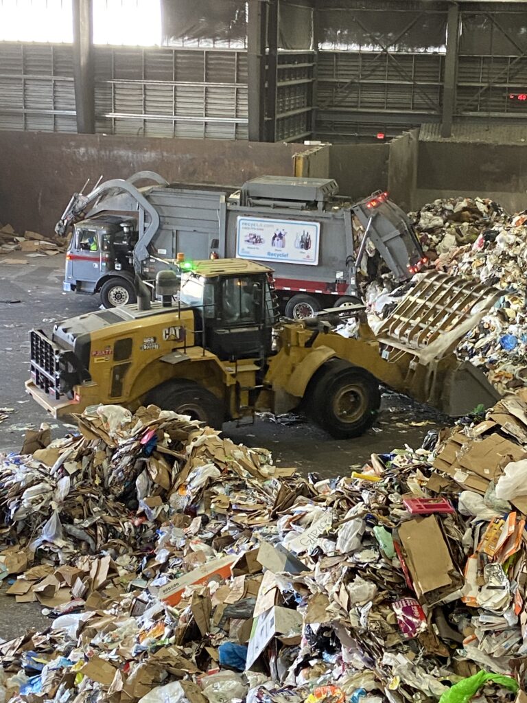 A bulldozer pushing mountains of trash towards the Athens Refuse Site machinery.