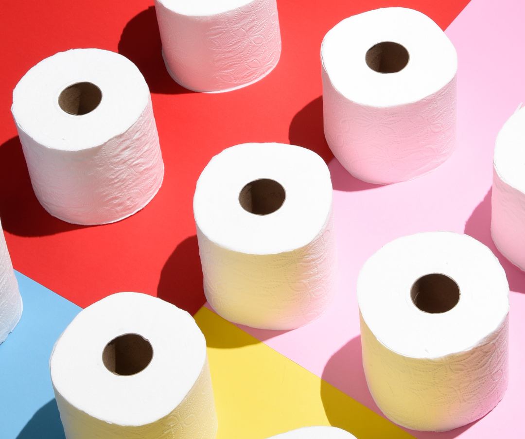 Toilet paper against a red, yellow, blue and yellow backdrop.