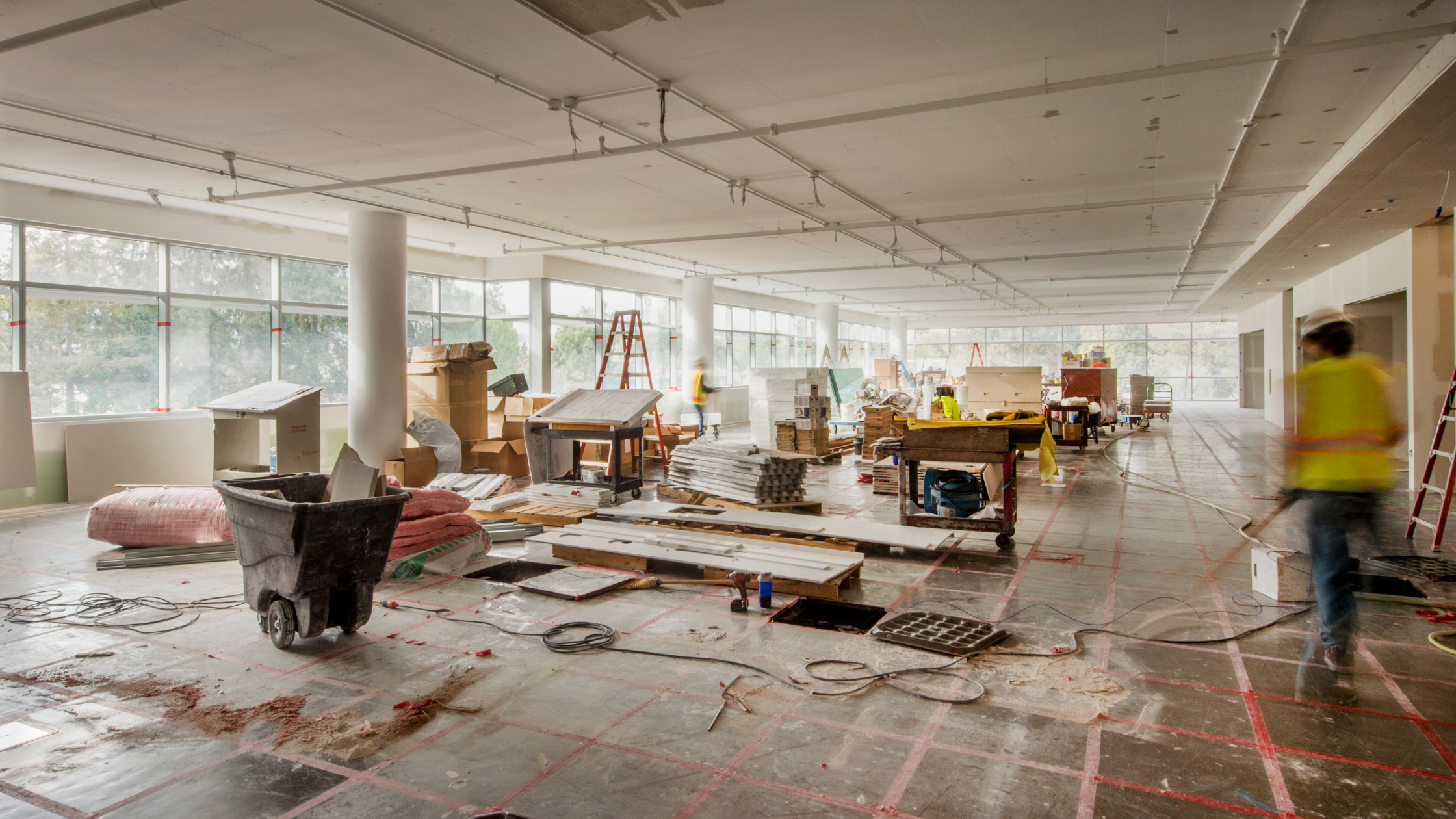 Construction Cleanup inside a commercial space where the floors are ripped out and carpentry is occurring.