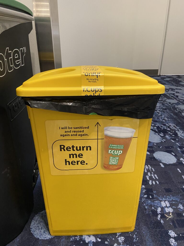 A yellow plastic dispenser for reusable cups called rcup found at the Las Vegas Waste Expo.